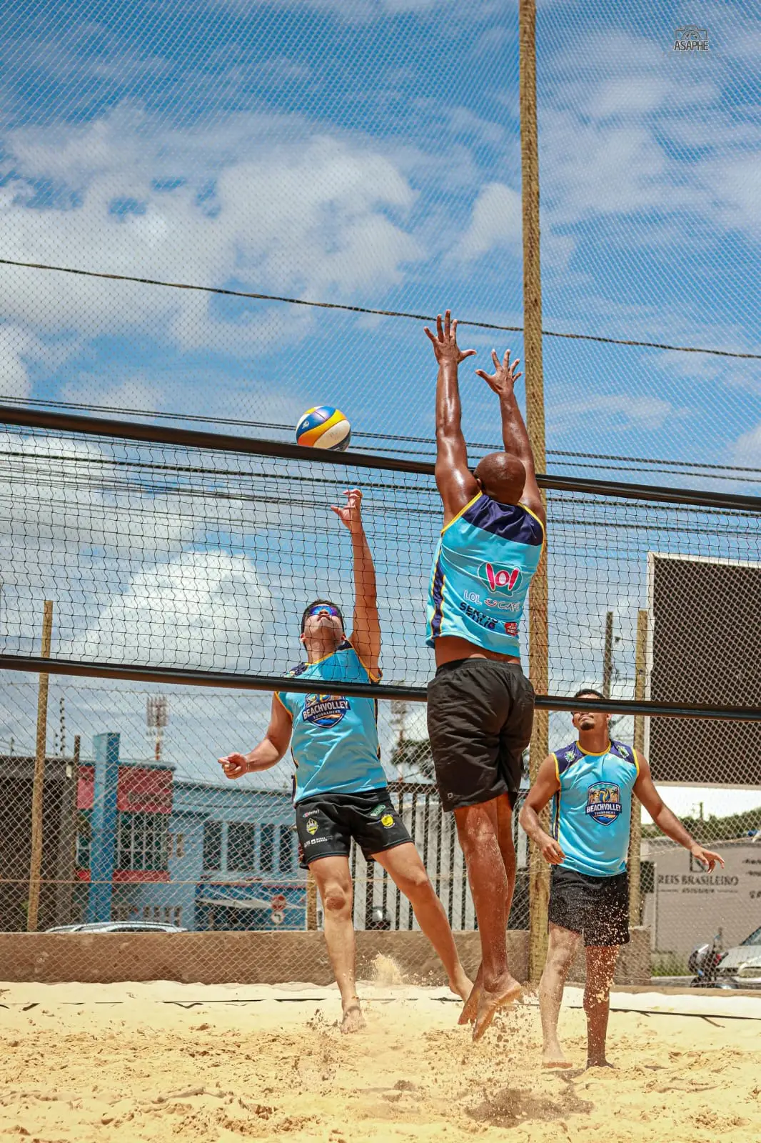 Jogadores de vôlei de praia saltando na rede durante um jogo no Ponto