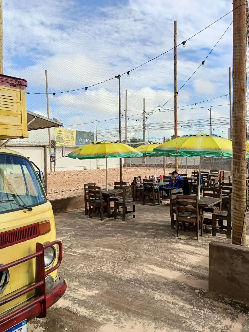 Mesas com guarda-sóis ao lado da Kombi amarela do Ponto