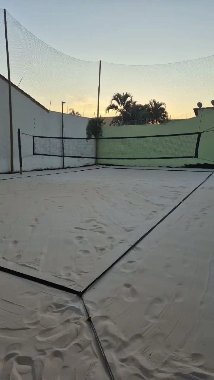 Quadra de areia vazia ao entardecer, com a rede armada
