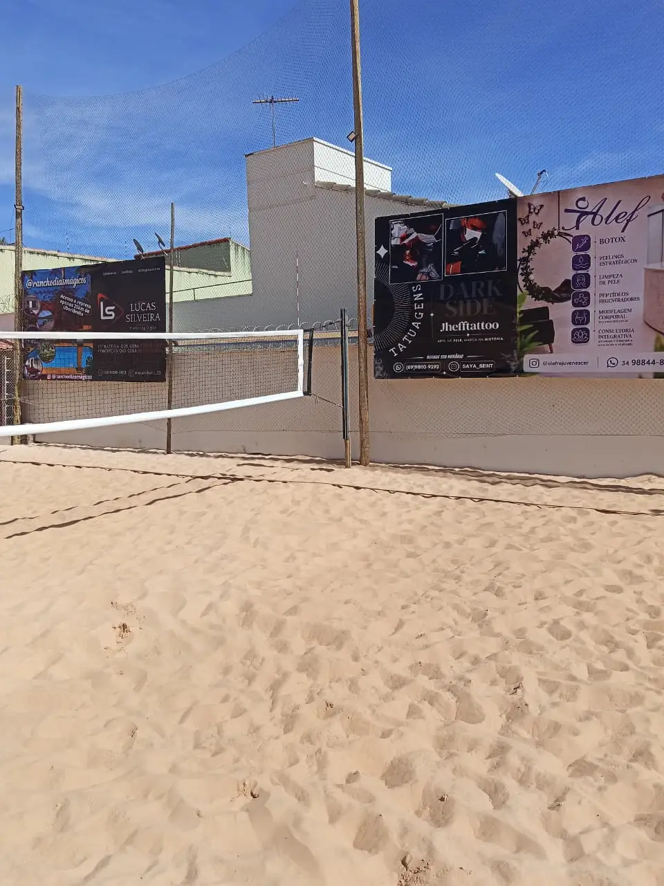 Banners de empresas na parede ao fundo da quadra de vôlei de praia